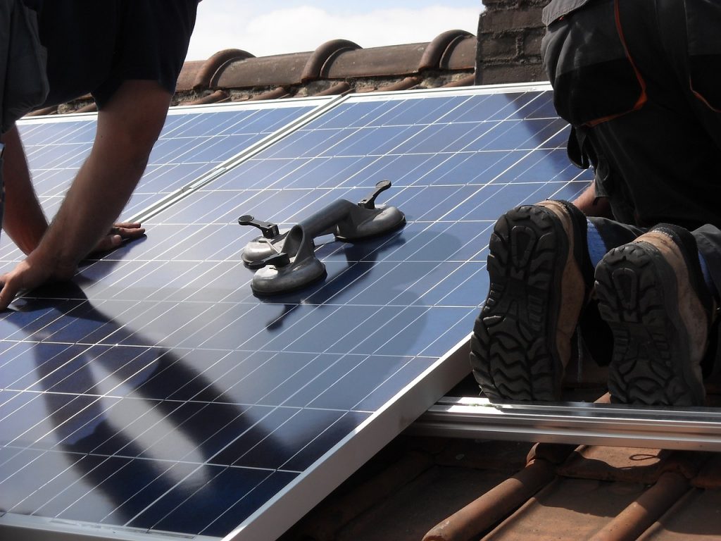 des installateurs de panneaux photovoltaïques sur un toit en tuile sous le soleil 