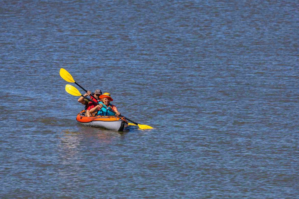 un couple en vacances en train de réparer leur kayak gonflable avant de pagayer dans l'eau