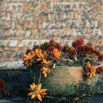 un pot de fleur devant une pierre tombale avec les étapes sur comment nettoyer le bronze sur les plaques funéraires pour son proche défunt