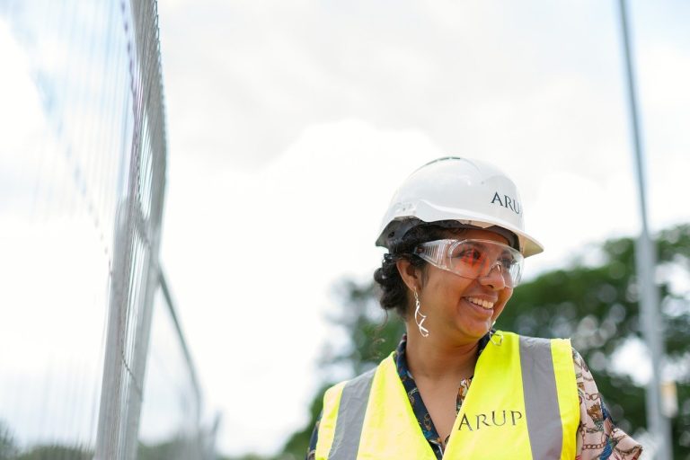 une femme portant un gilet jaune sur un chantier expliquant comment devenir ingénieur en génie civil à des jeunes élèves