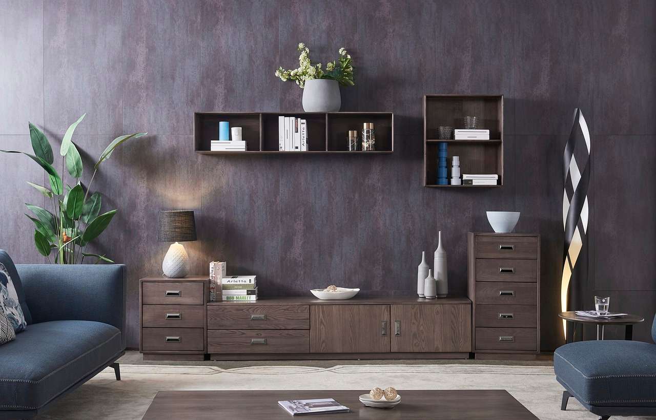 photo d'un bricoleur qui sait comment fixer un meuble au mur sans percer et ranger ses affaires dans son salon