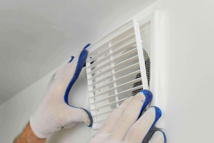 un professionnel installant une VMC dans une maison expliquant comment se fait le contrôle qualité de l'air d'une VMC ainsi que les économies d'énergies qui en résulte